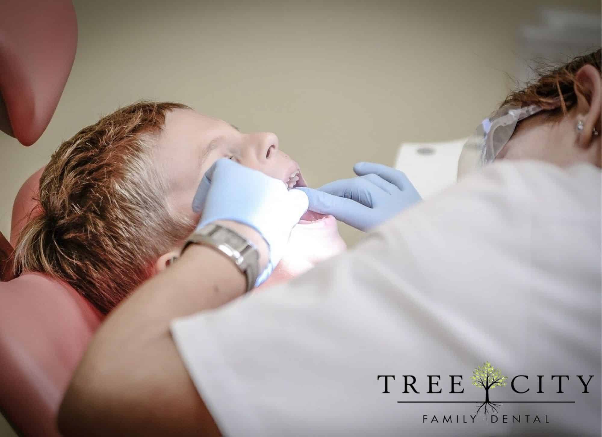 Young boy getting his teeth looked at by a female dentist.